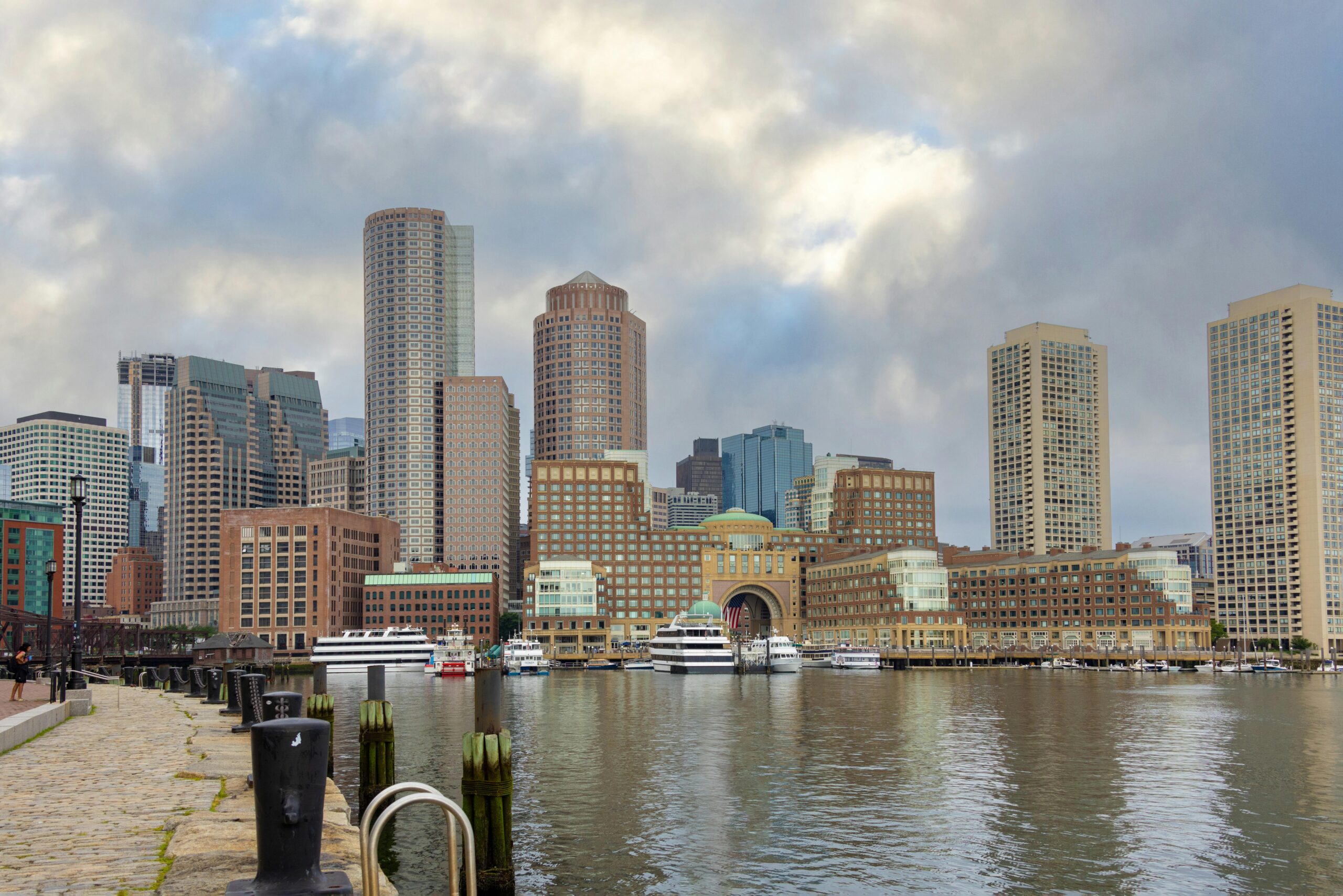 Panoramic view of Boston skyline with modern skyscrapers and harbor reflections, capturing urban architecture.