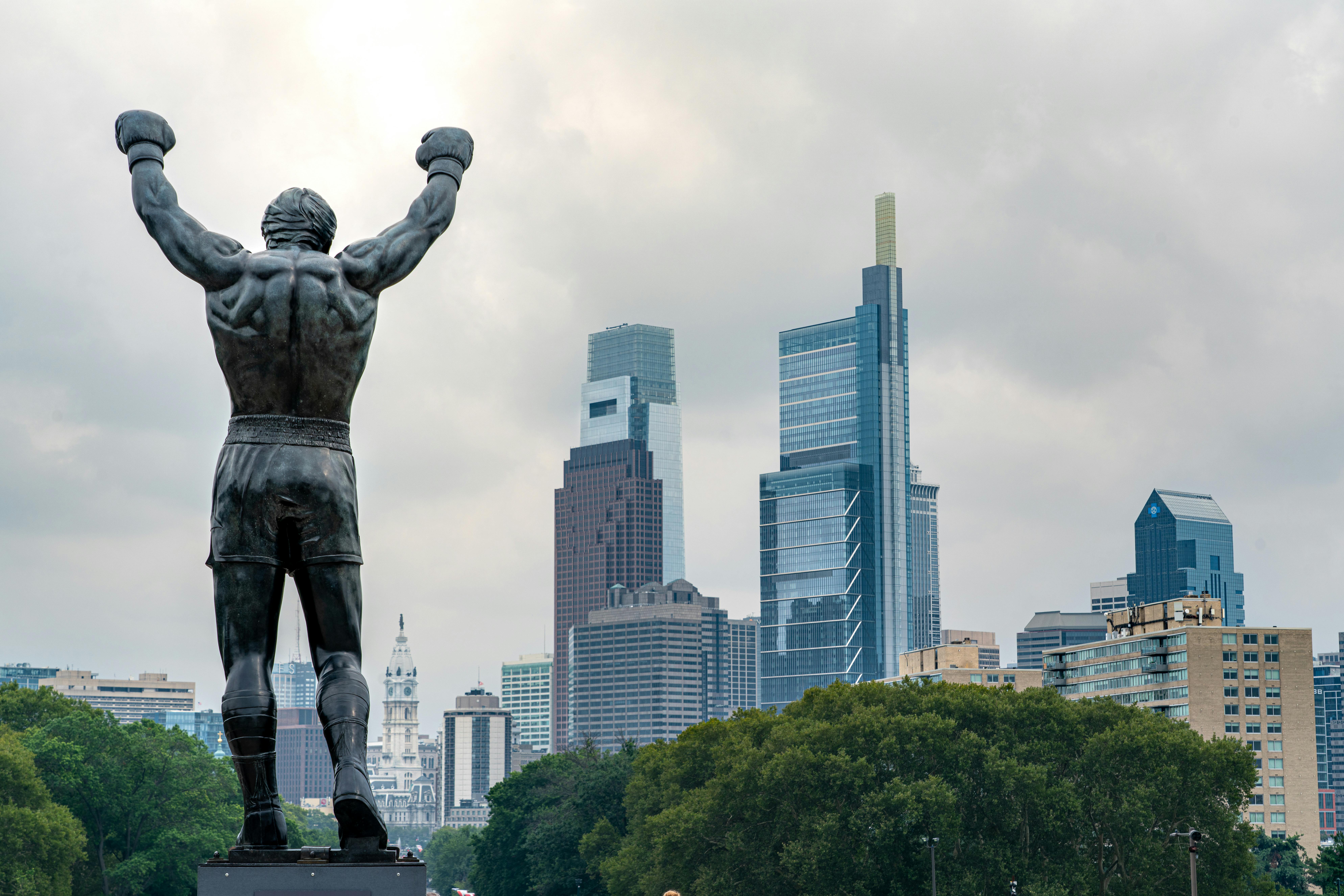 Statue of Rocky Balboa with arms raised against the Philadelphia skyline.